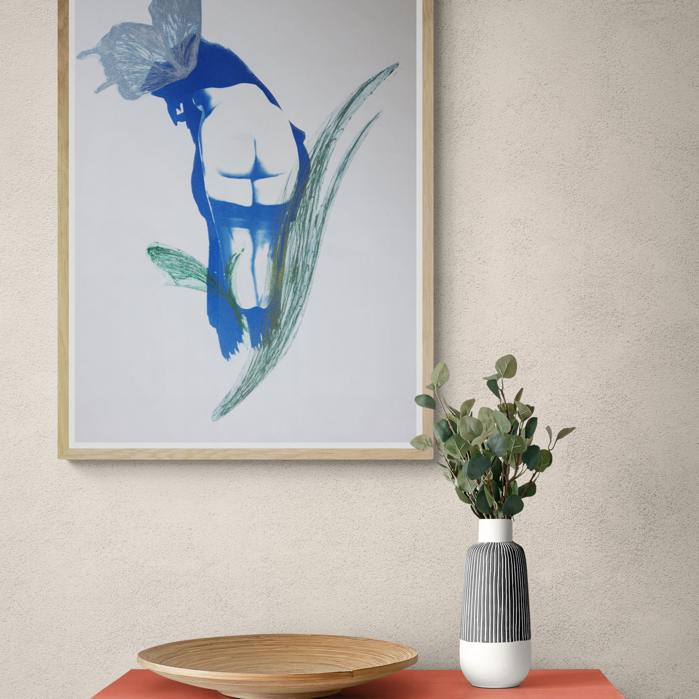 Œuvre de la collection Memoria encadrée, cyanotype et gravure sur papier, représentation d’un corps avec un papillon, teintes bleues et vertes, présentée en intérieur.
