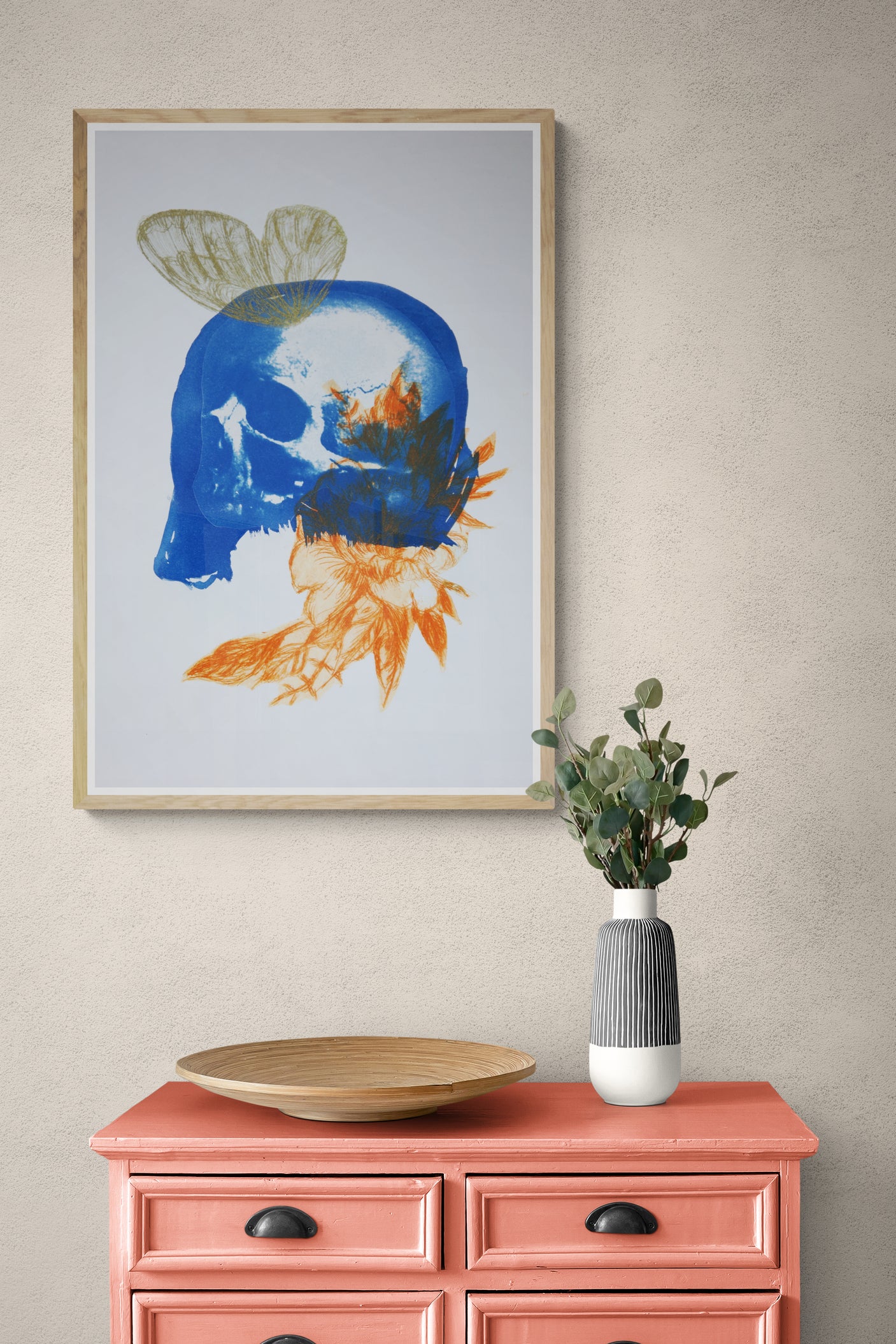 Œuvre de la collection Memoria encadrée, cyanotype et gravure sur papier, motif de papillon, de crâne et de fleur orange, présentée en intérieur.