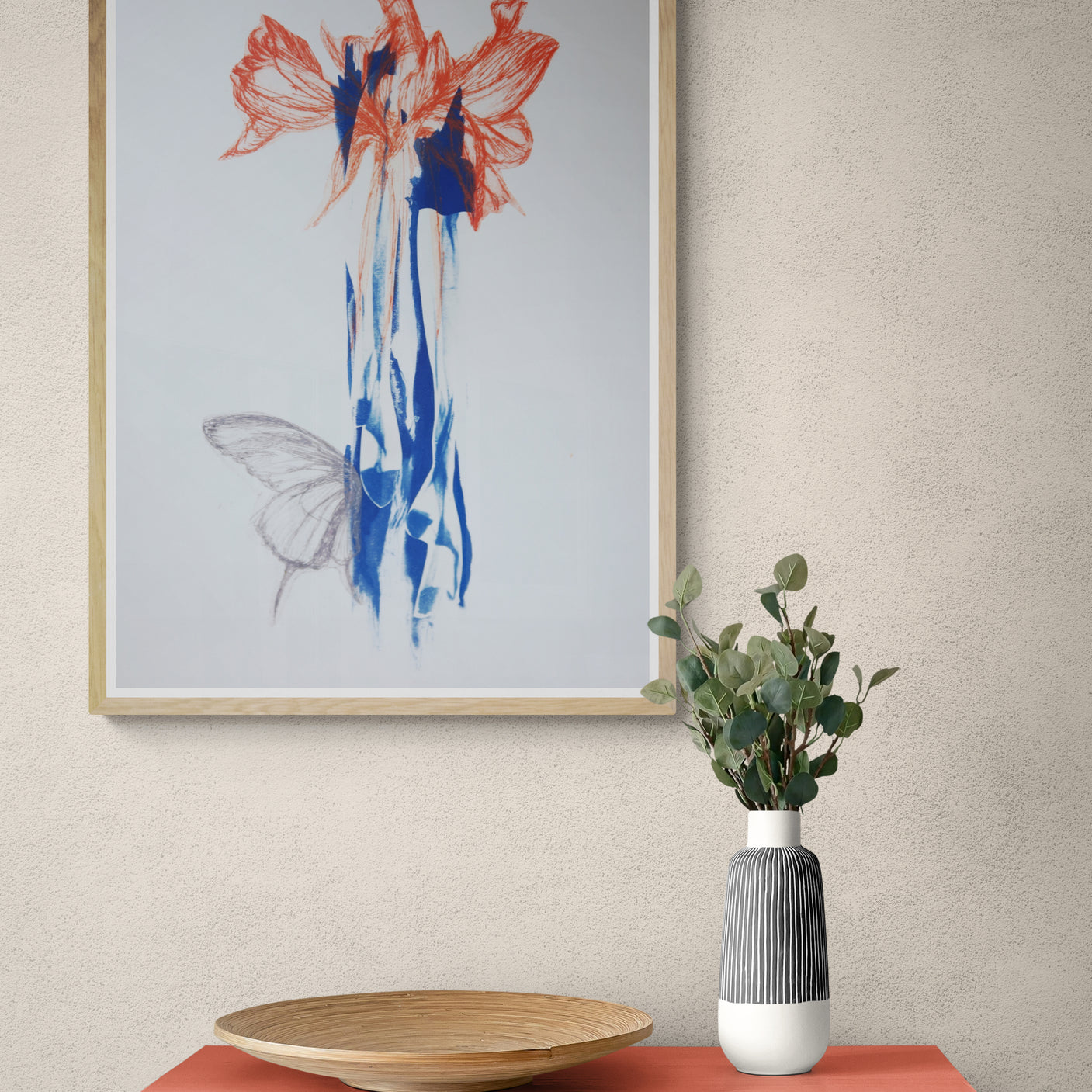 Œuvre de la collection Memoria encadrée, cyanotype et gravure sur papier, motif de papillon et de fleurs rouges, présentée en intérieur.