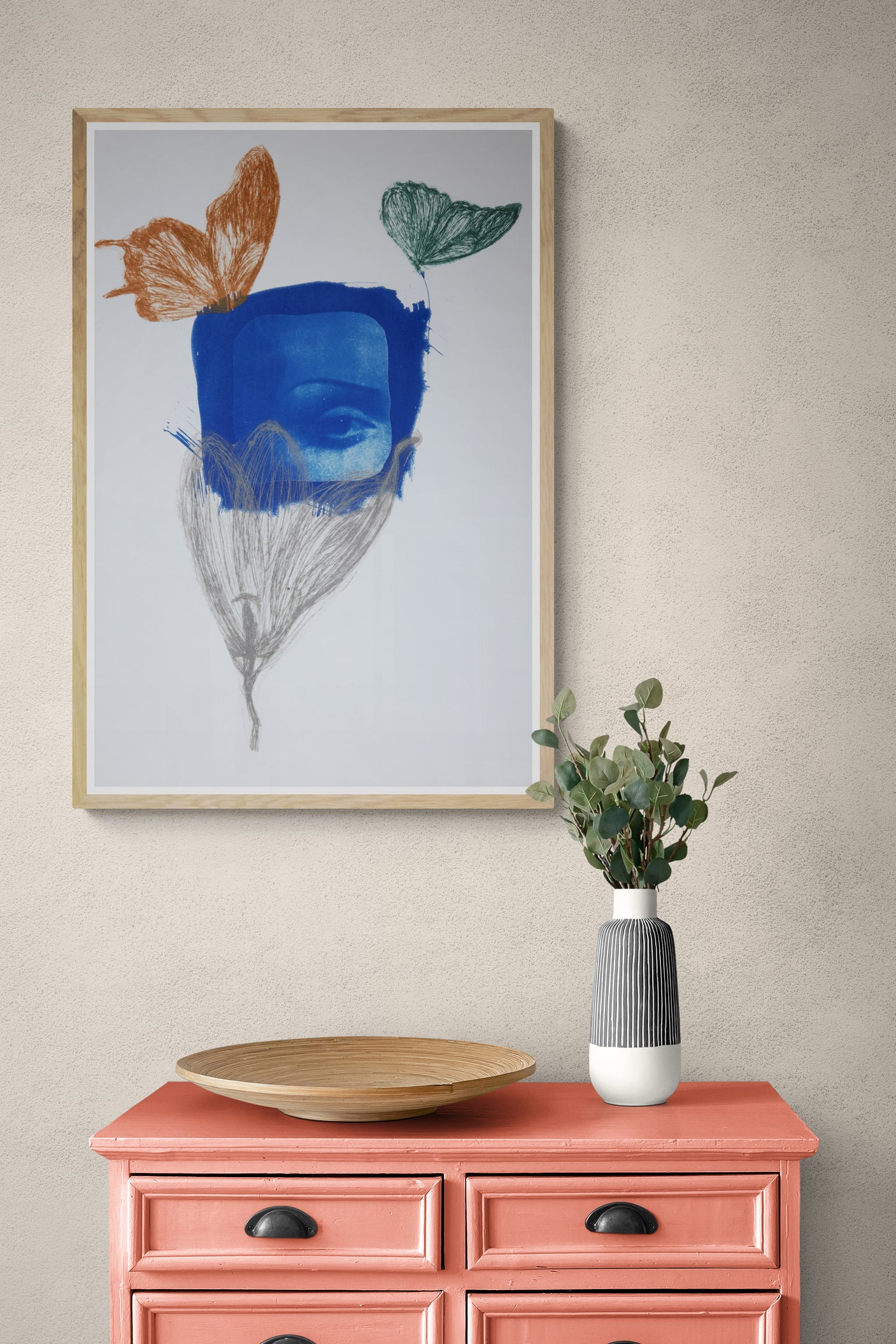 Œuvre de la collection Memoria encadrée, cyanotype et gravure sur papier, motif de papillons et d’un œil évoquant le regard, présentée en intérieur.