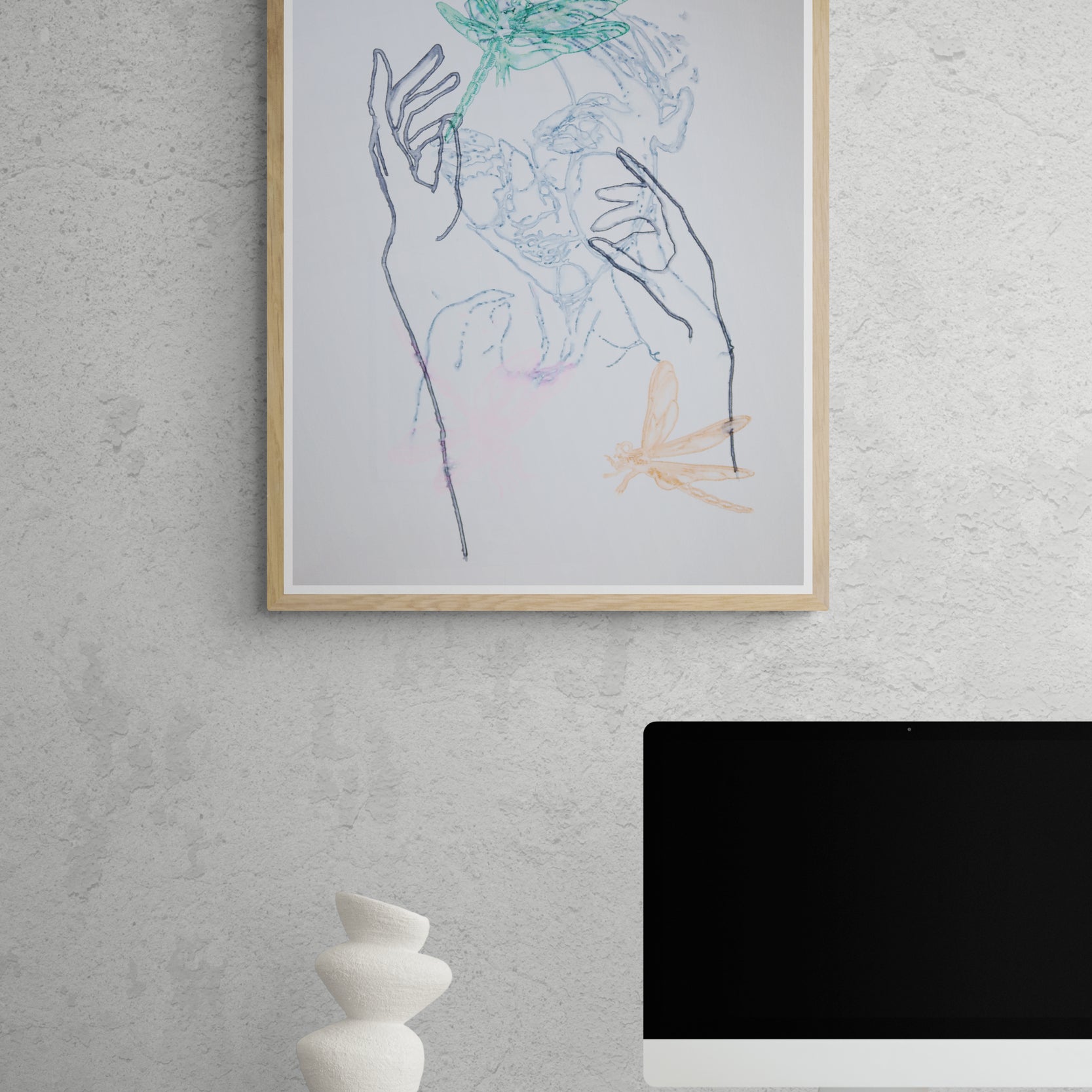 Œuvre de la collection Métamorphe encadrée, aquarelle sur papier, motif de libellules, de visage et de mains, aux teintes bleu, vert et rose, présentée en intérieur.