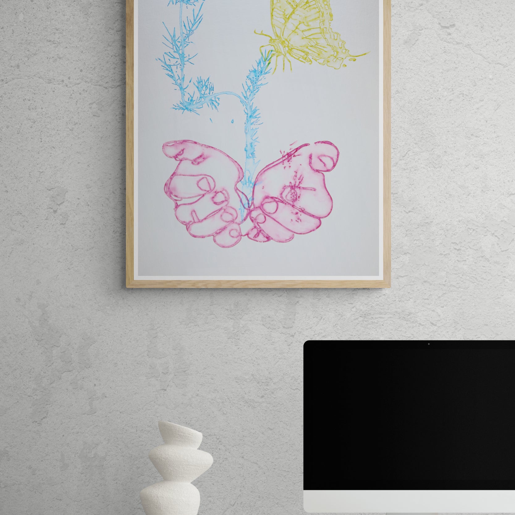 Œuvre de la collection Métamorphe encadrée, aquarelle sur papier, motif de mains et de papillon, aux teintes rose, bleu et jaune, présentée en intérieur.