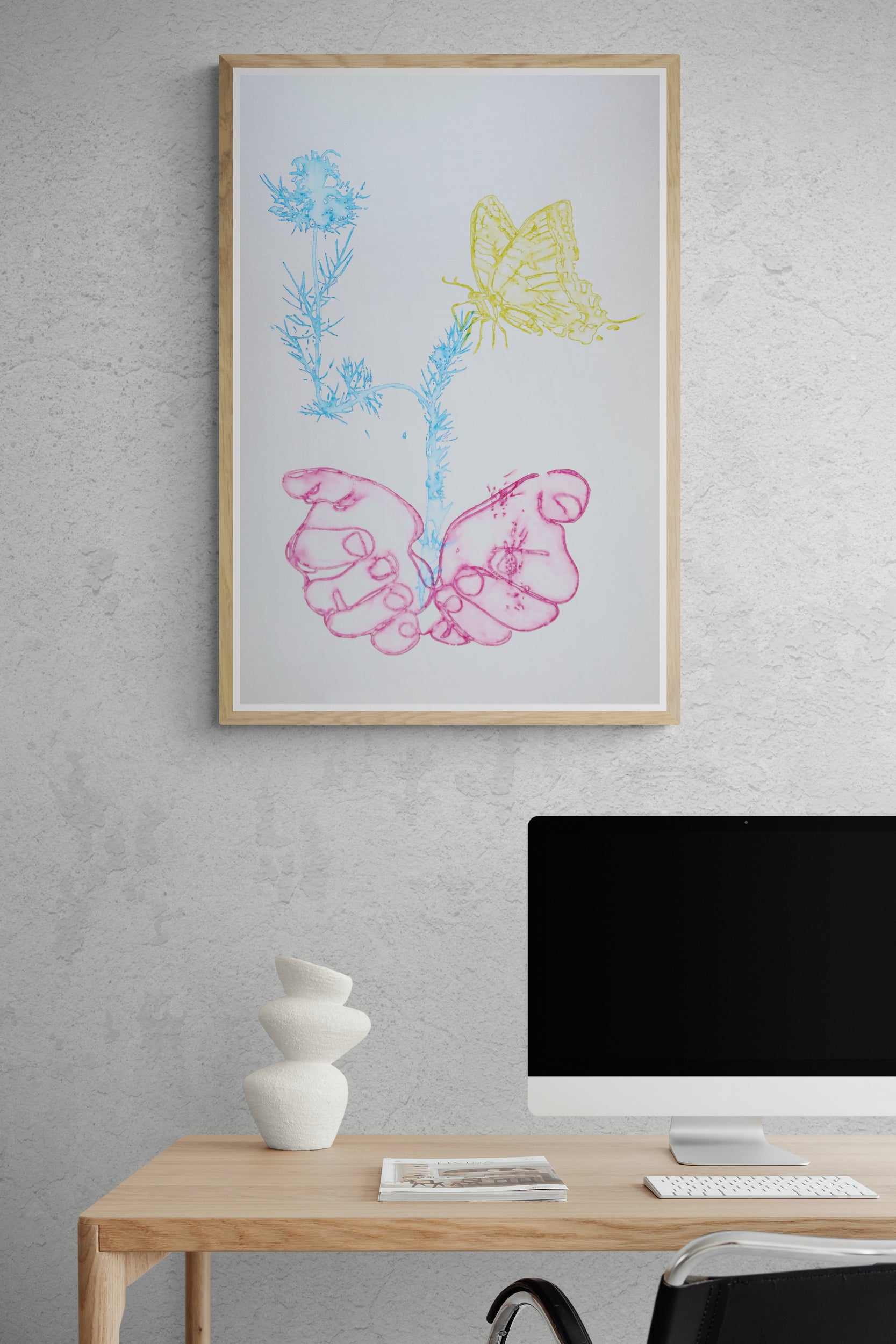 Œuvre de la collection Métamorphe encadrée, aquarelle sur papier, motif de mains et de papillon, aux teintes rose, bleu et jaune, présentée en intérieur.