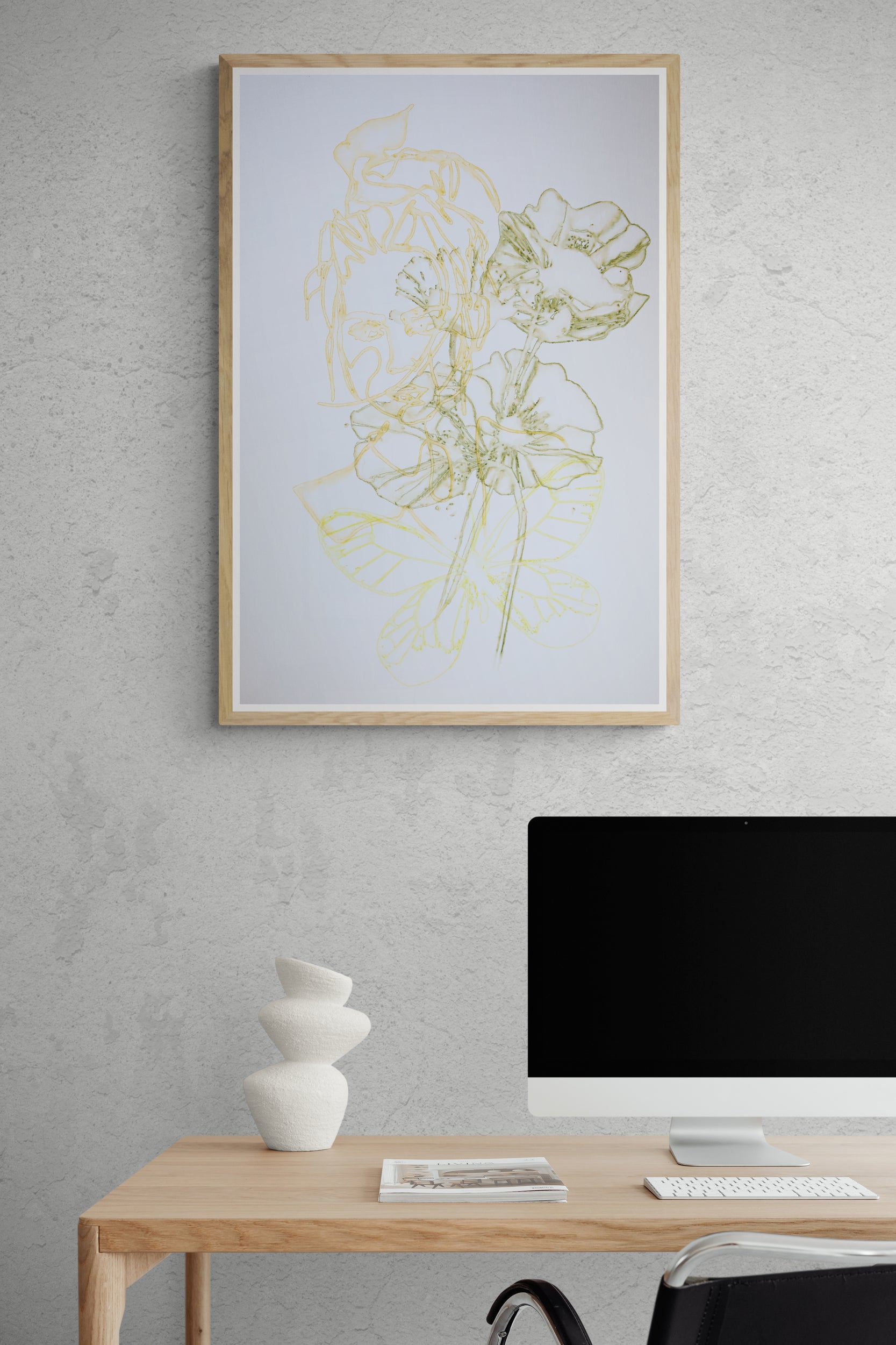 Œuvre de la collection Métamorphe encadrée, aquarelle sur papier, motif de visage, de fleur et de papillon, aux teintes jaune, vert et orange, présentée en intérieur.
