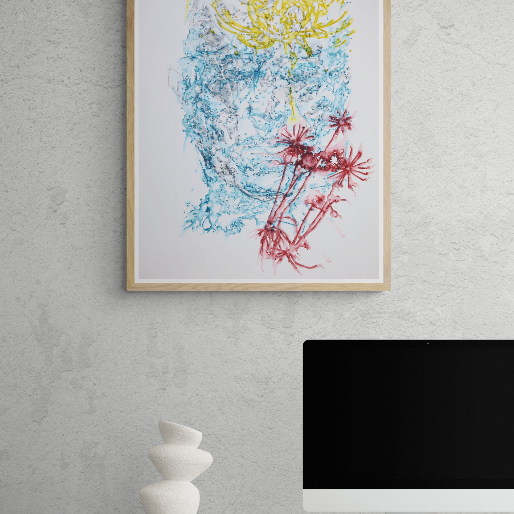 Œuvre de la collection Métamorphe encadrée, aquarelle sur papier, motif de visage et de fleurs, aux teintes bleu, jaune et rouge, présentée en intérieur.
