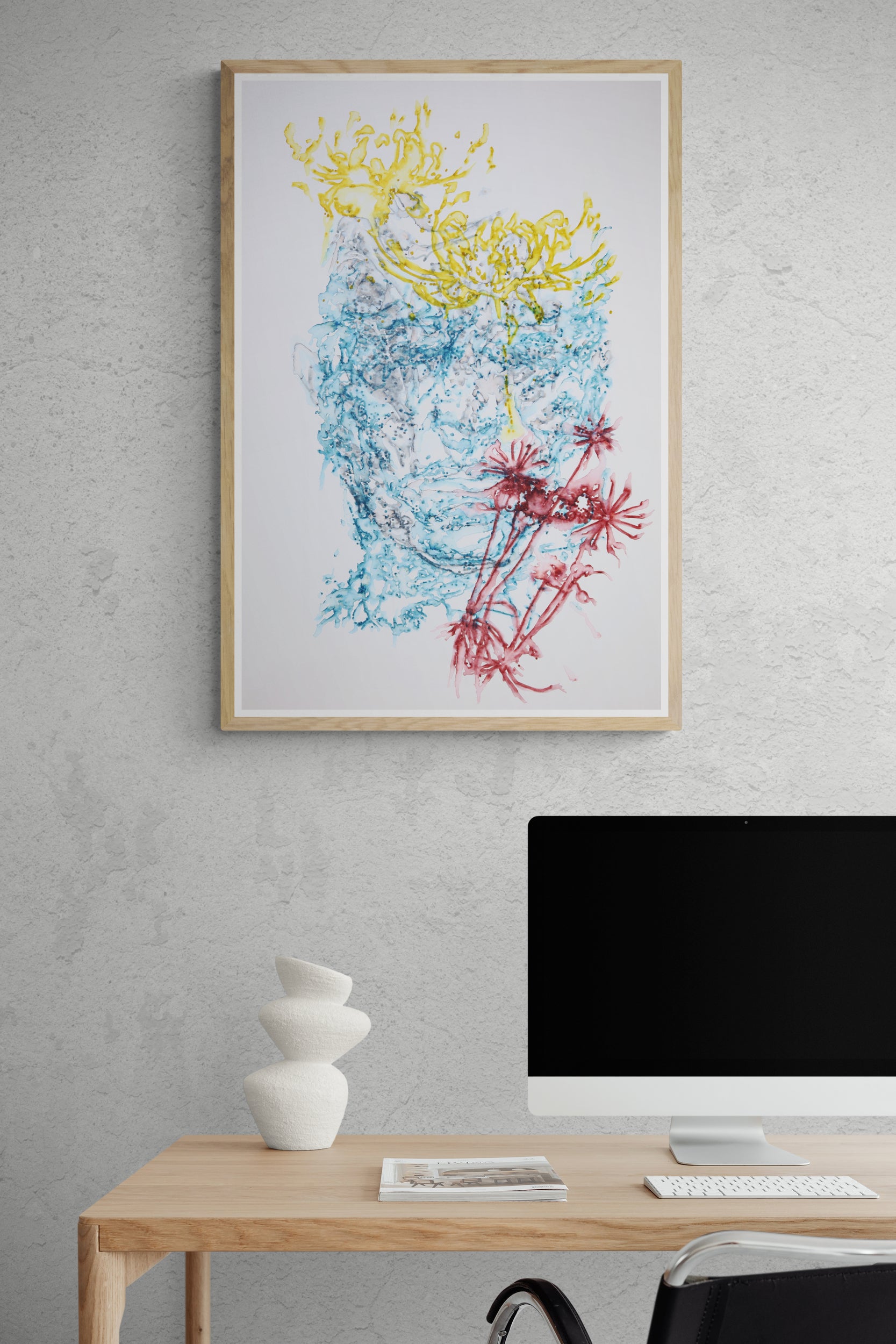 Œuvre de la collection Métamorphe encadrée, aquarelle sur papier, motif de visage et de fleurs, aux teintes bleu, jaune et rouge, présentée en intérieur.