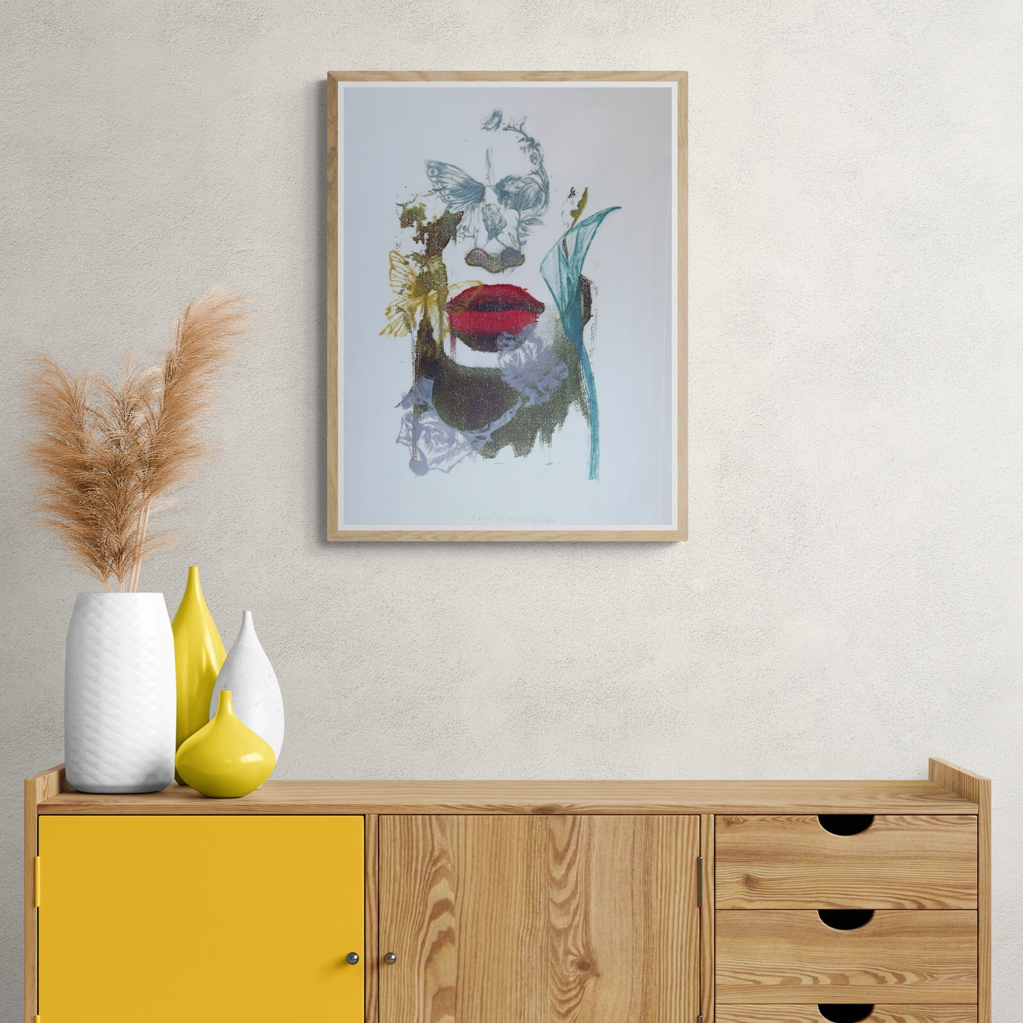 Œuvre encadrée de la collection Spiritus, gravure et image imprimée sur papier, visage fondu avec d’autres éléments, bouche rouge et papillon, présentée en intérieur.