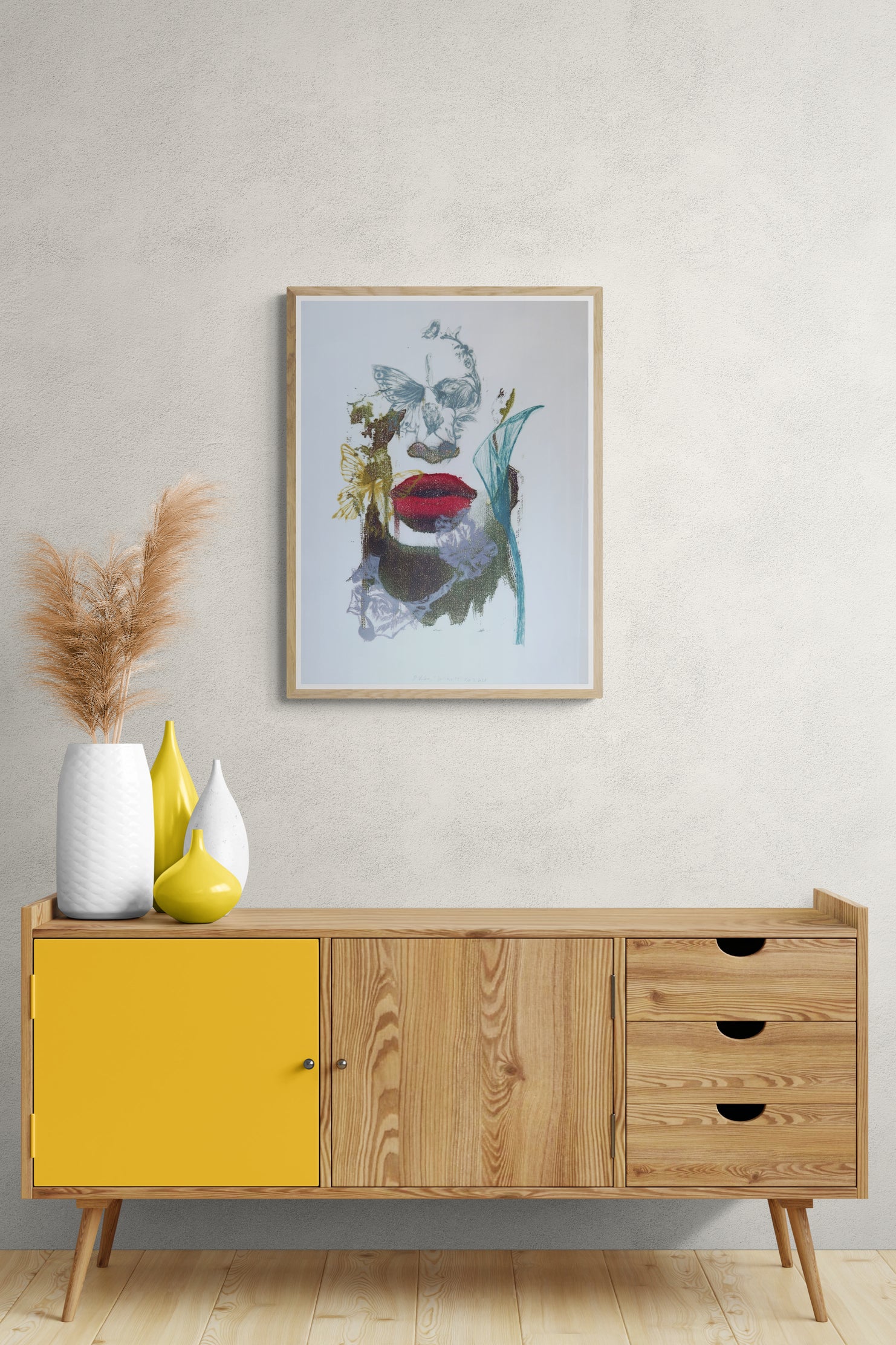 Œuvre encadrée de la collection Spiritus, gravure et image imprimée sur papier, visage fondu avec d’autres éléments, bouche rouge et papillon, présentée en intérieur.